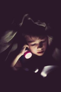 little boy reading in the dark